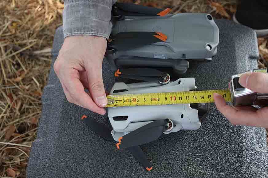 Die DJI Air 2S und die DJI Mini 3 Pro liegen zusammengefaltet nebeneinander und die Größe wird gemessen.